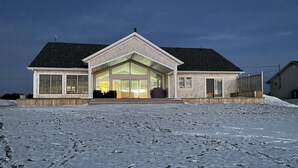 Ein zweistöckiges Haus mit einer großen Veranda, einer Garage und einer verschneiten Auffahrt.