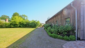 A gravel path leading to a rustic wooden building with a brick entrance. - Ehemaliges Farmhaus Lehsten (Lehsten)