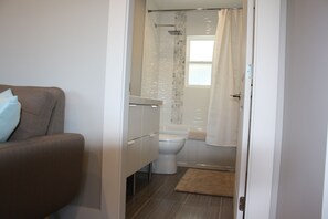 A bathroom with a toilet, shower, and a towel rack. - Central House (Chilliwack)