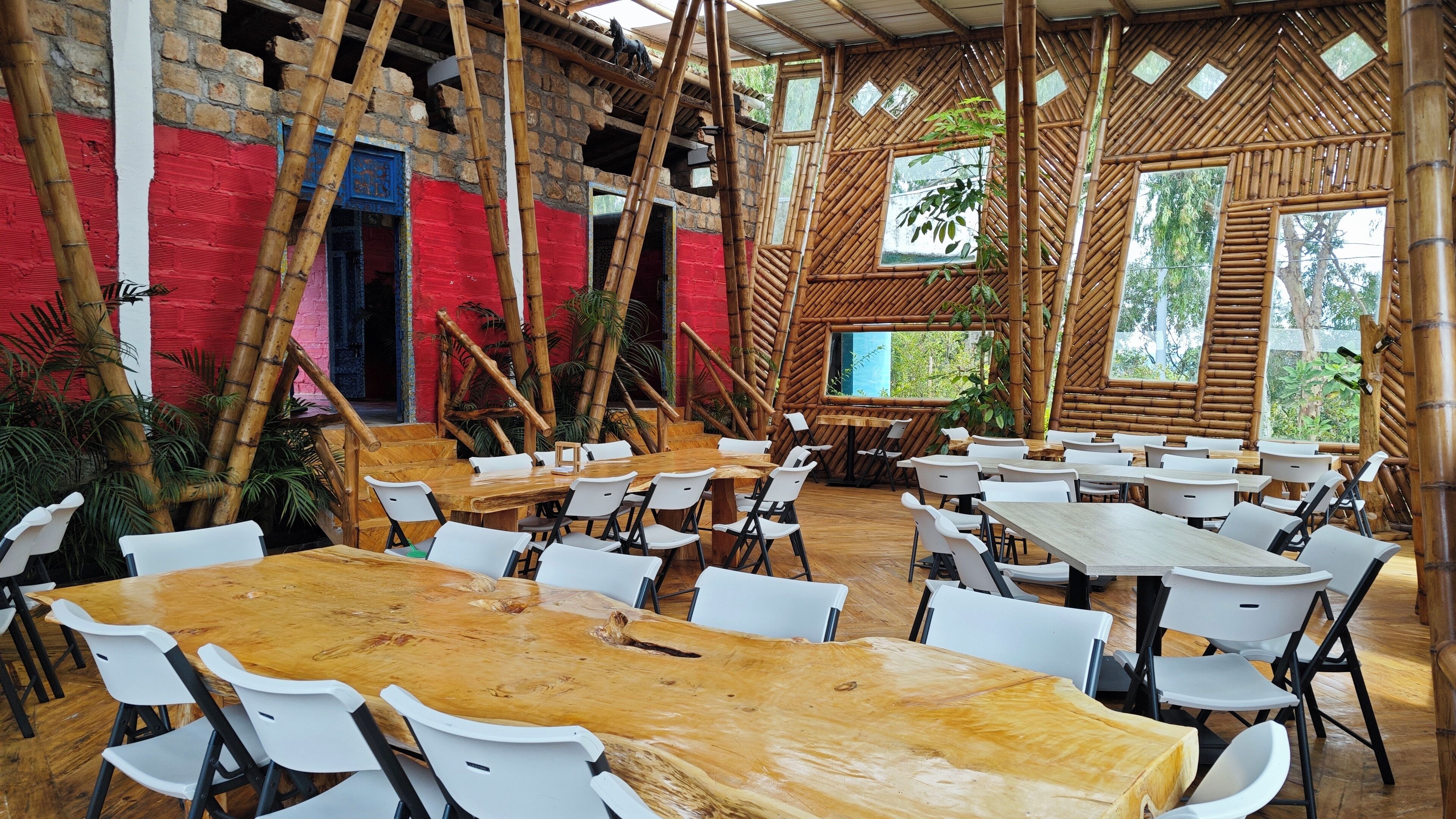 A restaurant with bamboo walls and a mix of wooden and white tables.