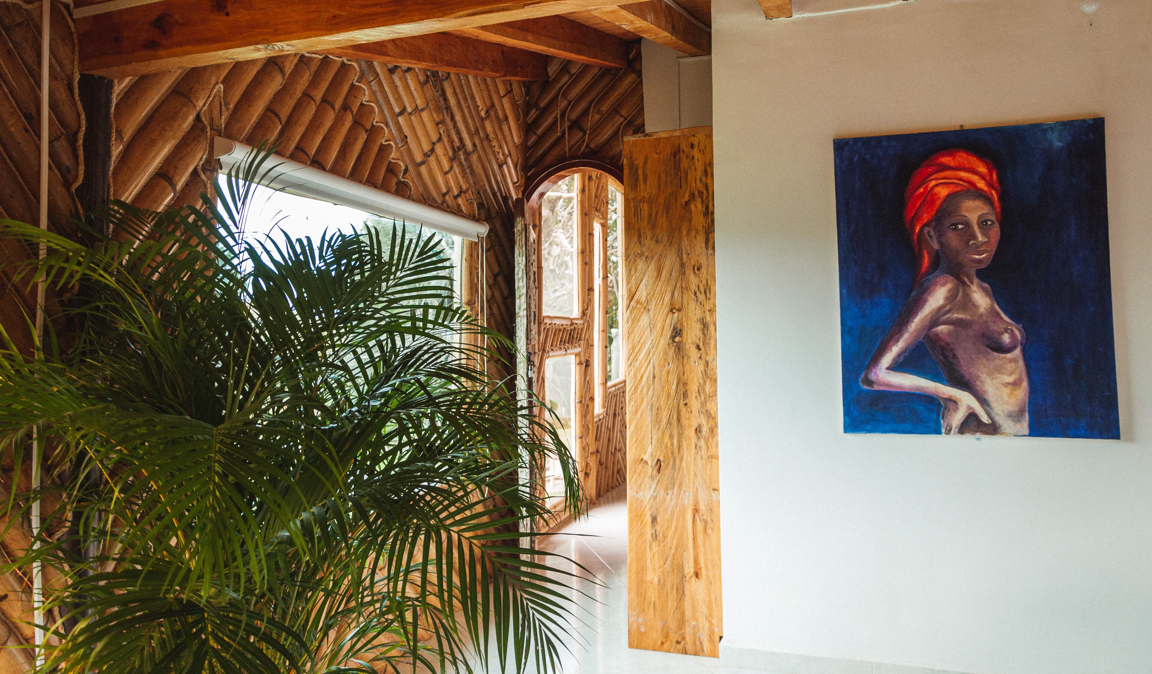Een kamer met een houten plafond, een grote plant en een schilderij aan de muur.
