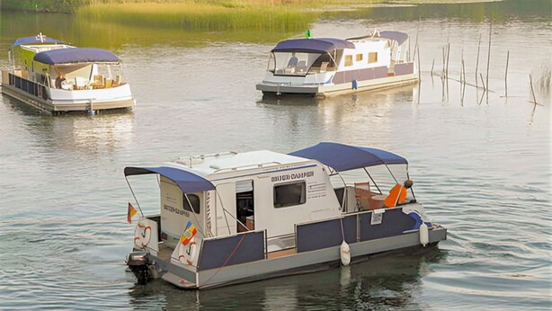 A houseboat with a covered deck, a small cabin, and a motor at the front. - Nice ship in Verchen with kitchen (Verchen)