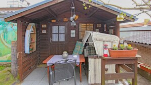 A wooden cabin with a table and chairs, a hanging light fixture, and a potted plant.