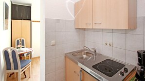 A compact kitchen with a sink, stove, and wooden cabinets.
