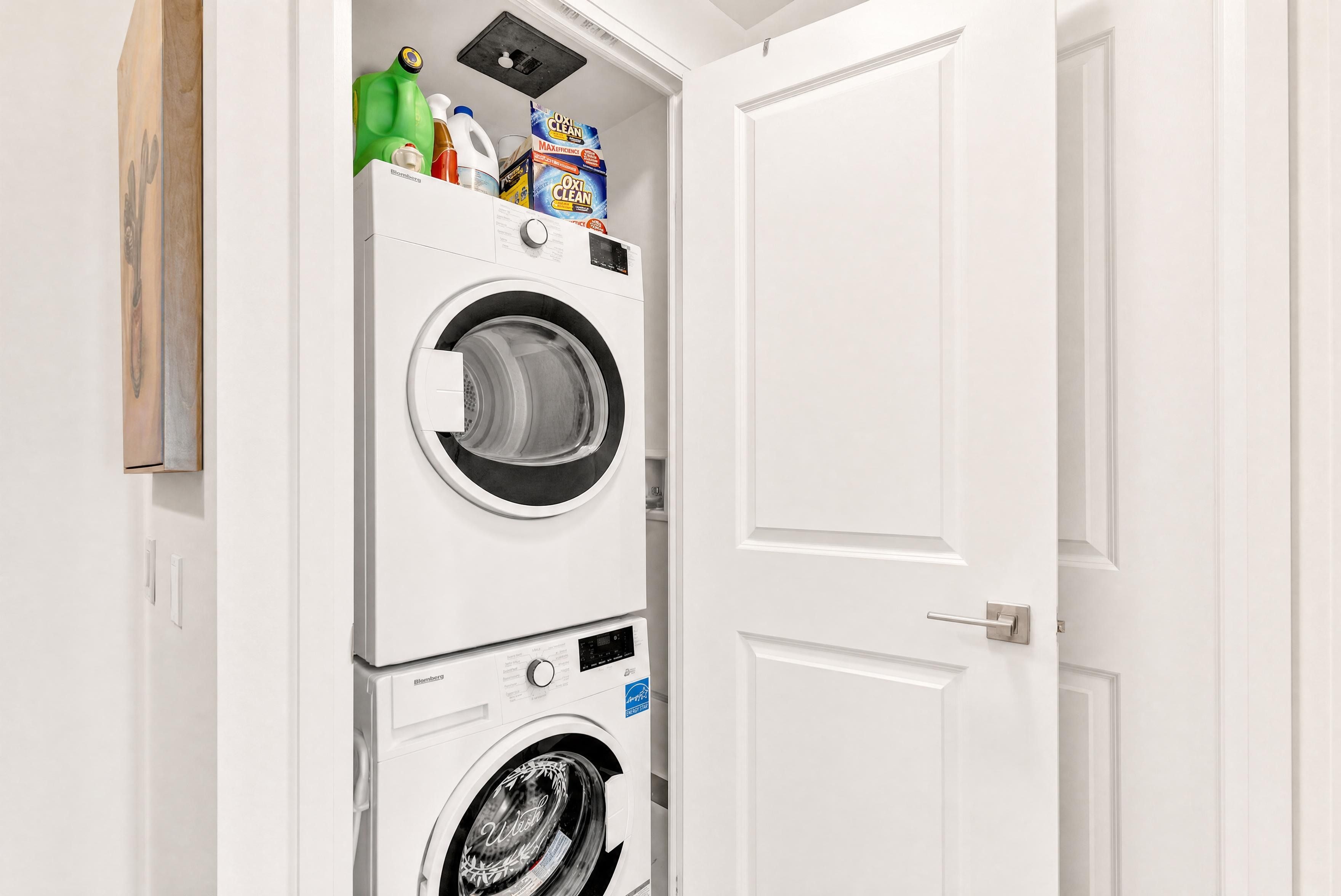 A white wall with a double-door closet containing two front-loading washing machines.