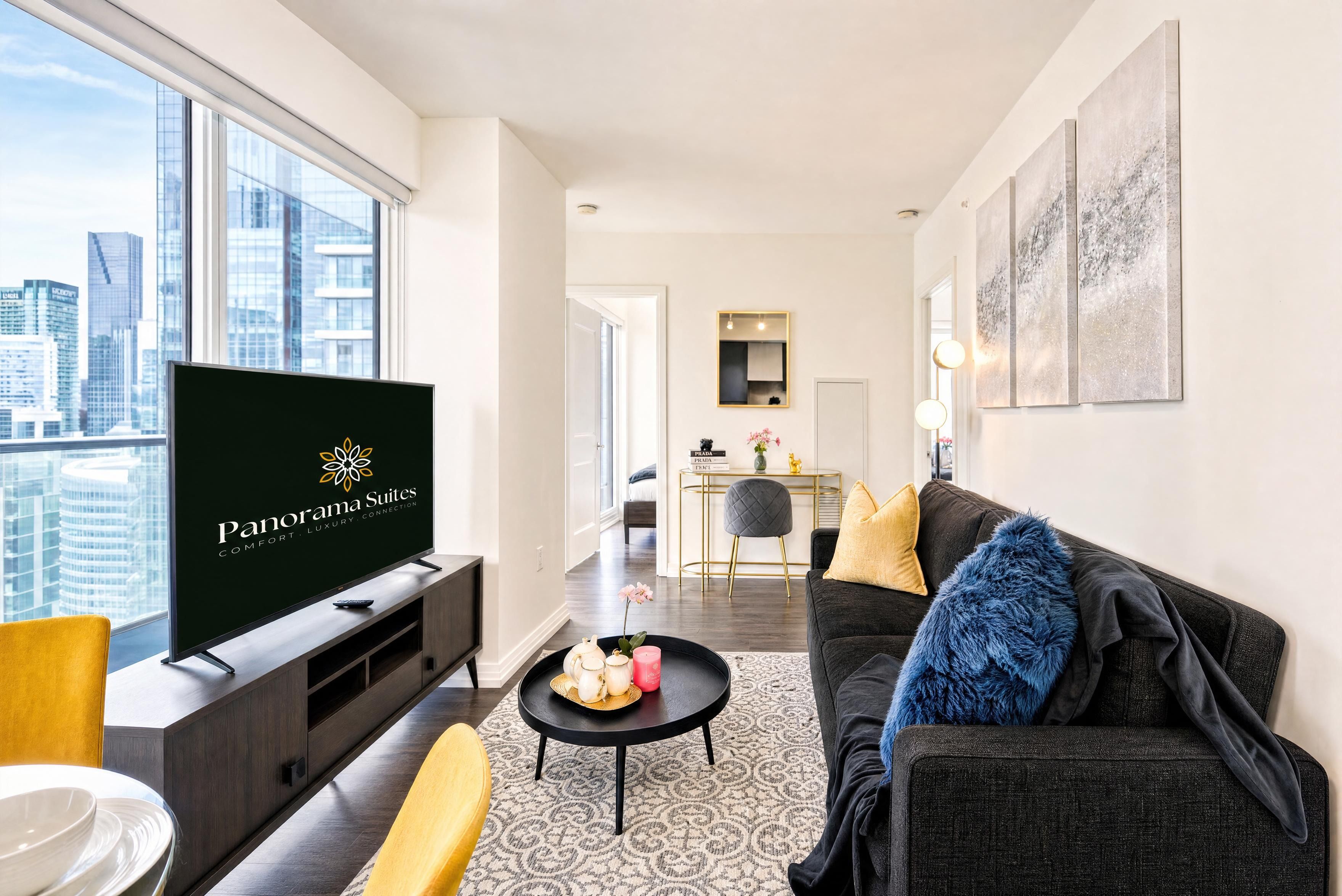 Een moderne woonkamer met een grote televisie, een bank, een salontafel en een uitzicht op de stad door grote ramen.