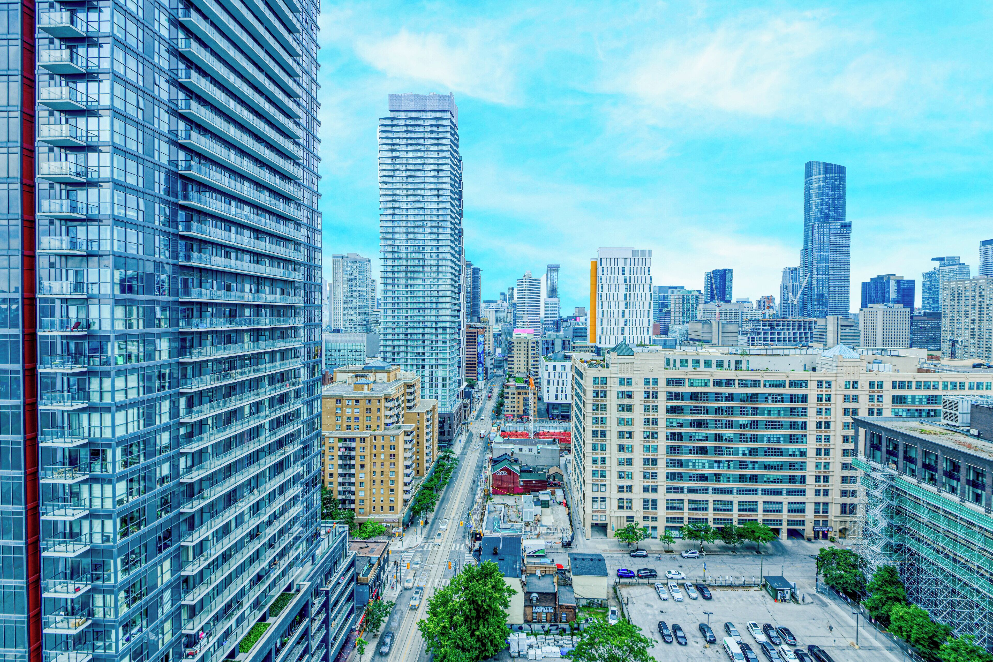 A high-rise urban area with modern buildings, a parking lot, and a clear sky.