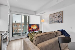 Een moderne woonkamer met een bank, een flatscreen televisie en een schilderij aan de muur.