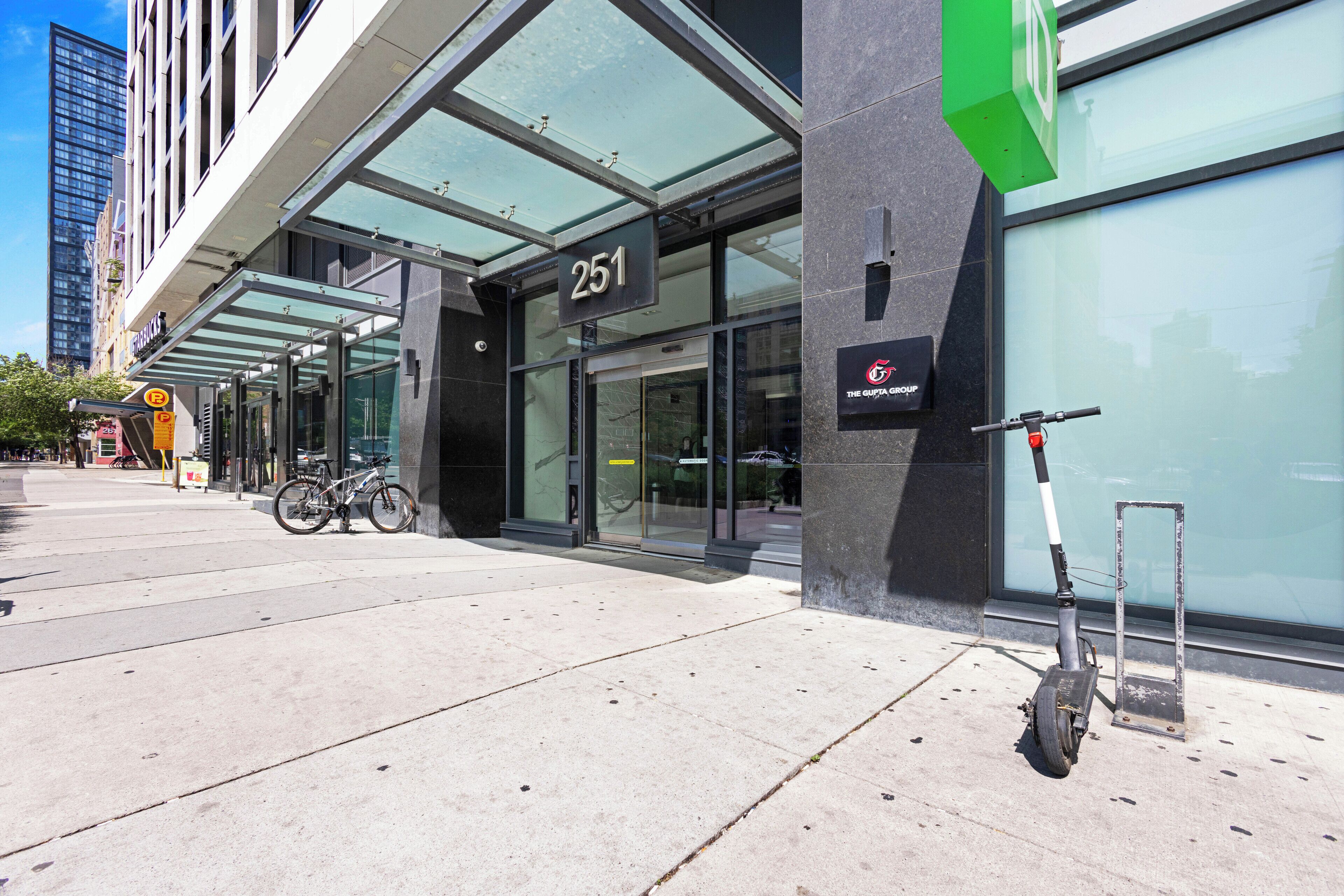 A modern building with a glass entrance, numbered 251, and a scooter parked outside.