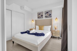 Een slaapkamer met een bed, nachtkastjes, een wandlamp en een plafondlamp.