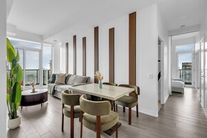 A modern living room with a dining area, large windows, and a city view.