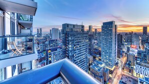 A high-rise building with a modern glass facade, multiple floors, and a view of a cityscape at sunset. - Panorama Suites (Toronto)