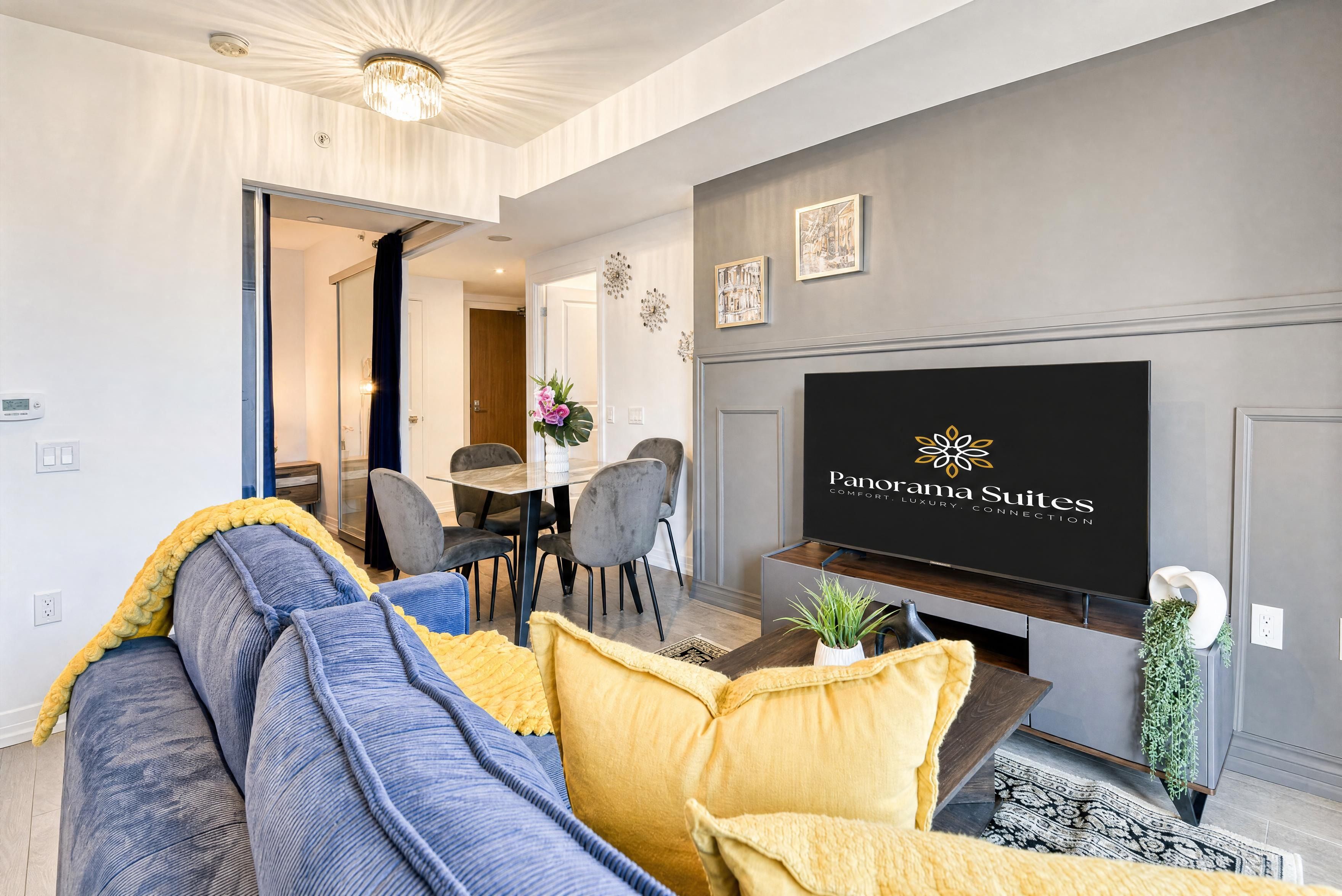 A modern living room with a sofa, a coffee table, and a flat-screen TV mounted on the wall.