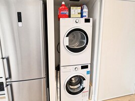 Una cocina compacta con un refrigerador de acero inoxidable y una lavadora-secadora apilada.