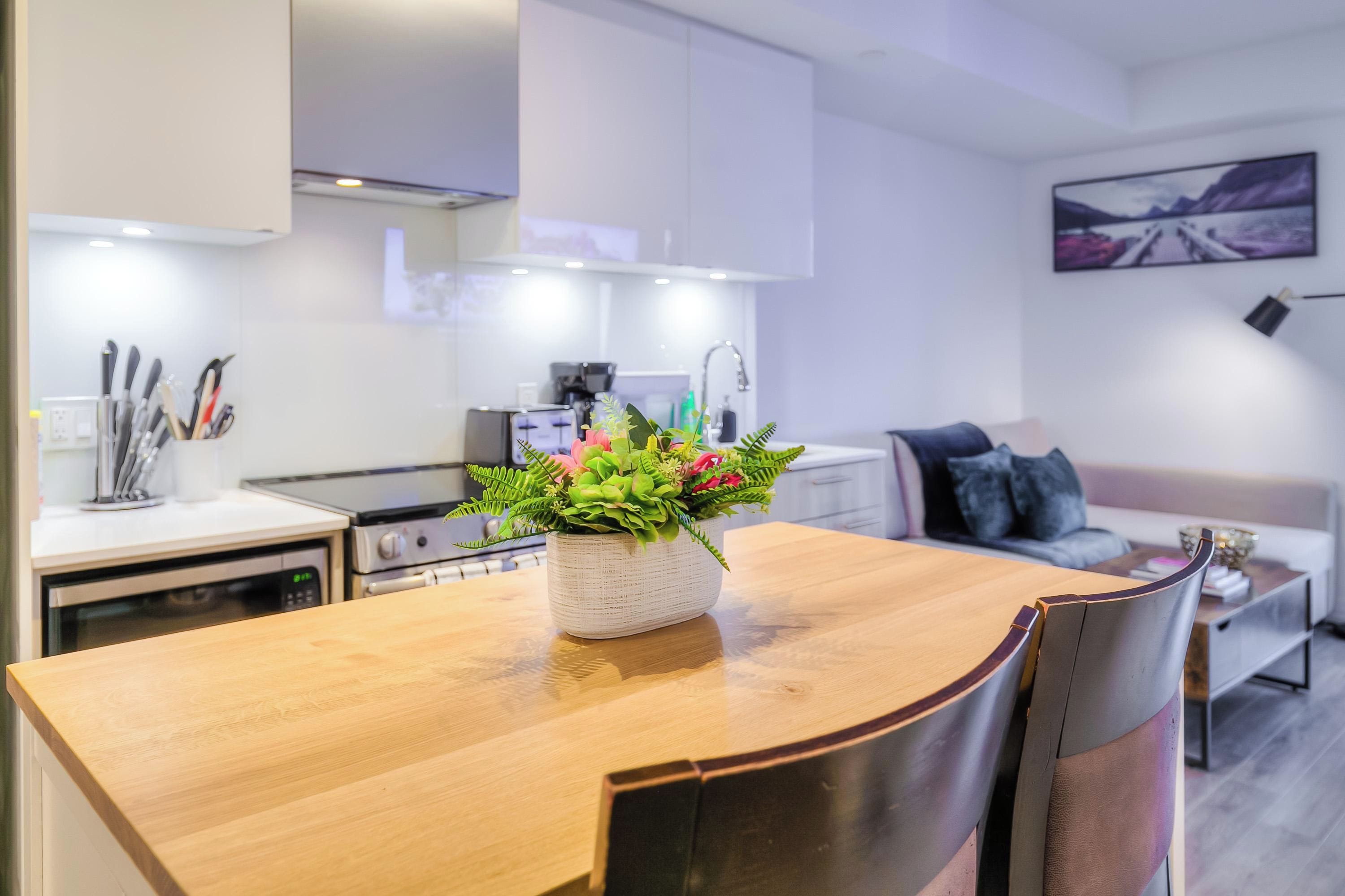 Una cocina moderna con armarios blancos, una mesa de comedor de madera y una planta en maceta.