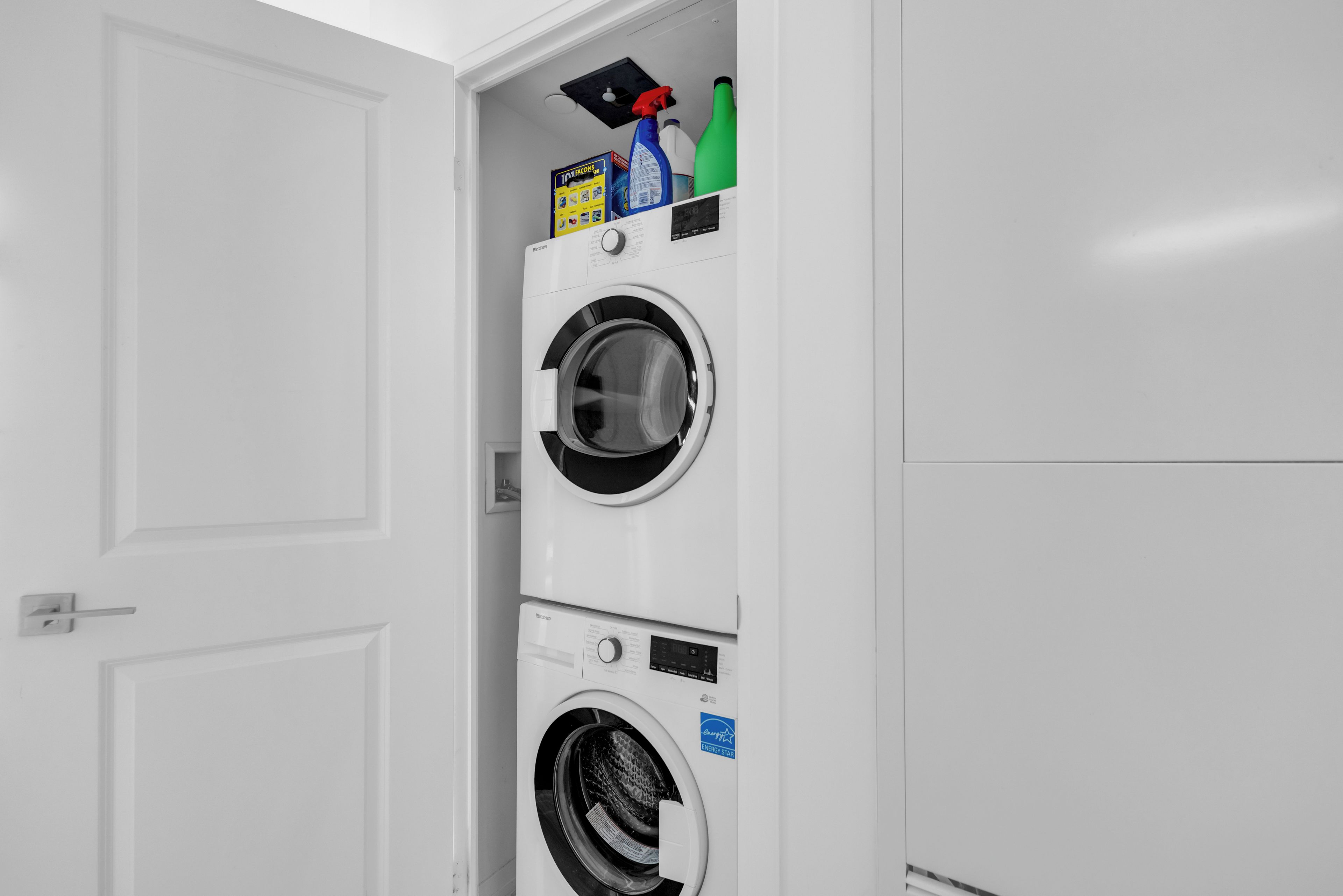 A stacked washer and dryer unit with a door to the left.