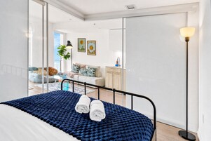 Een moderne slaapkamer met een bed, een blauwe deken en twee opgerolde handdoeken.