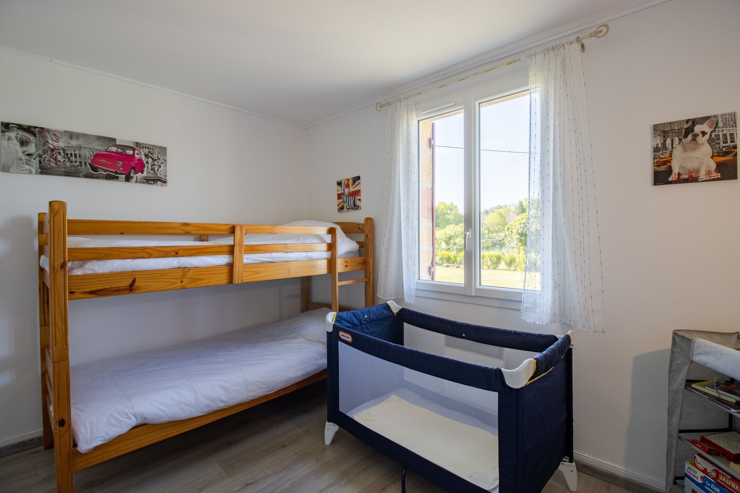 Una habitación con literas, una ventana con cortinas y una estantería.
