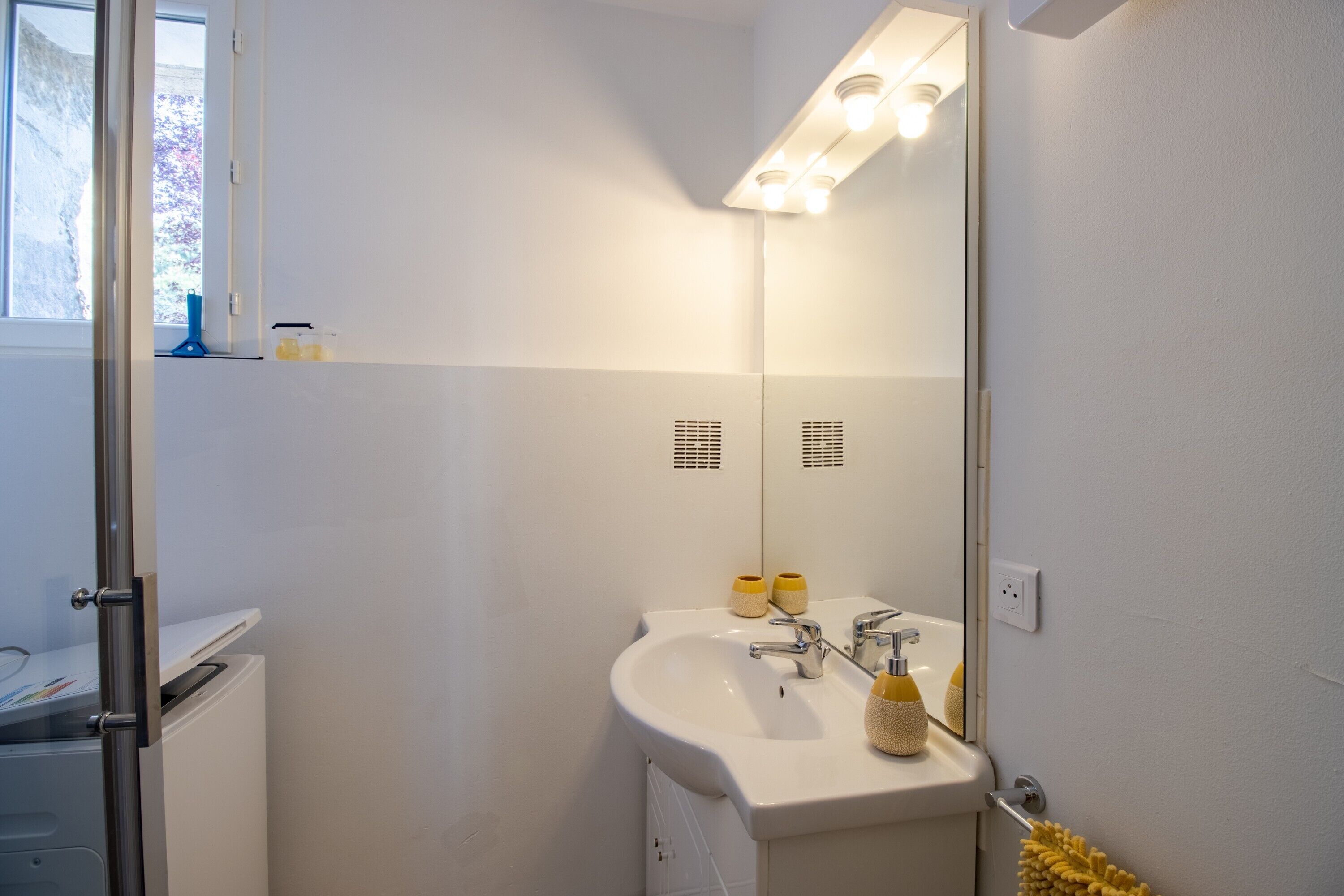 Casa de banho com lavatório branco, espelho e porta-toalhas.