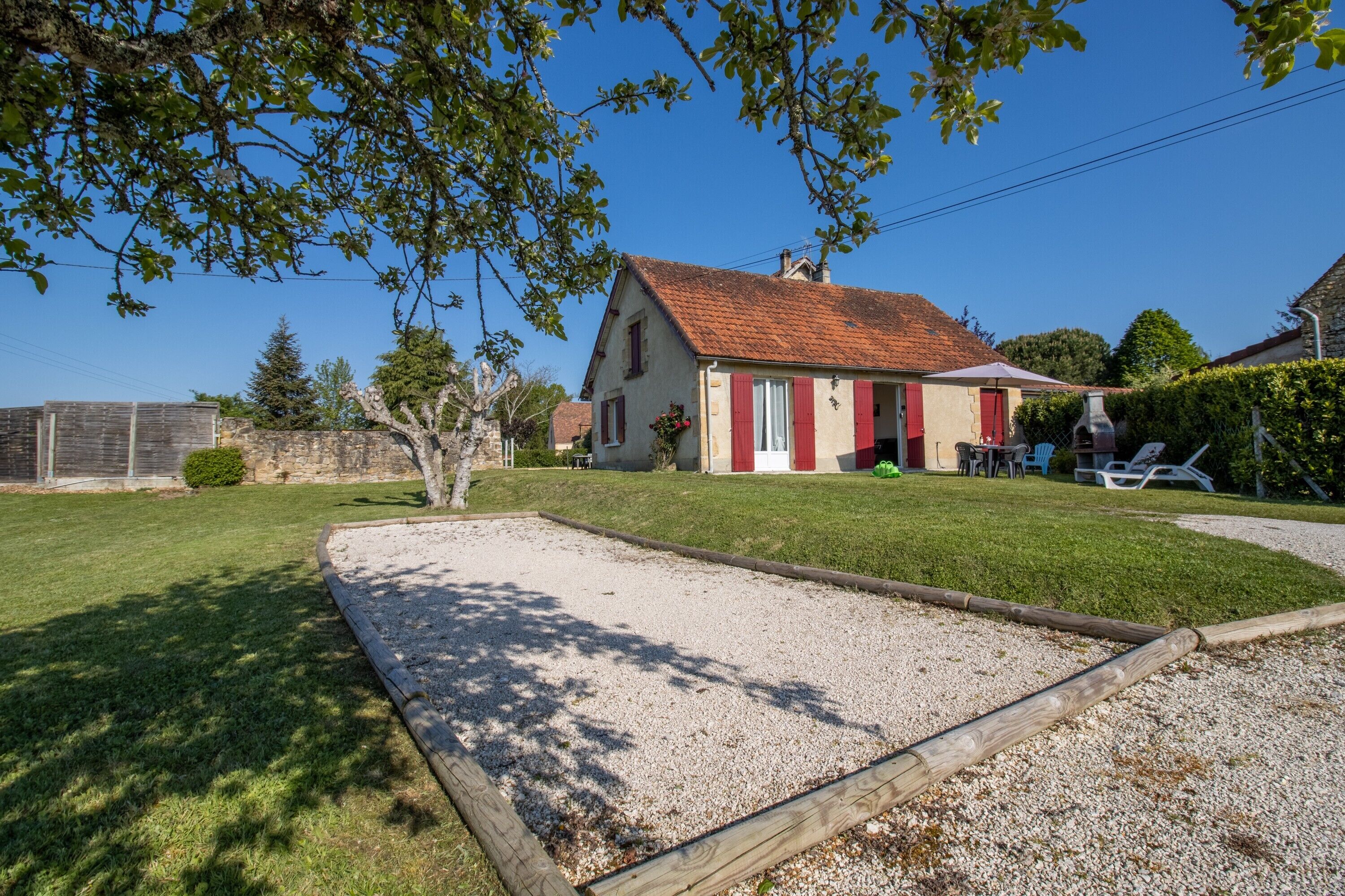 A house with a red roof, a gravel area, and a lawn.