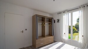 A bedroom with a bed, a wardrobe with a mirror, and a window with curtains. - Gîte La Salamandre – Renovated Haven of Peace near Sarlat (Saint-André-d'Allas)