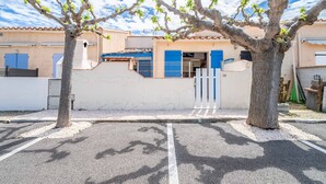 A parking lot with a tree in the foreground, a building with blue shutters, and a clear sky. - Holiday Home 'Fleurynes' with Terrace and Private Garden (Fleury)