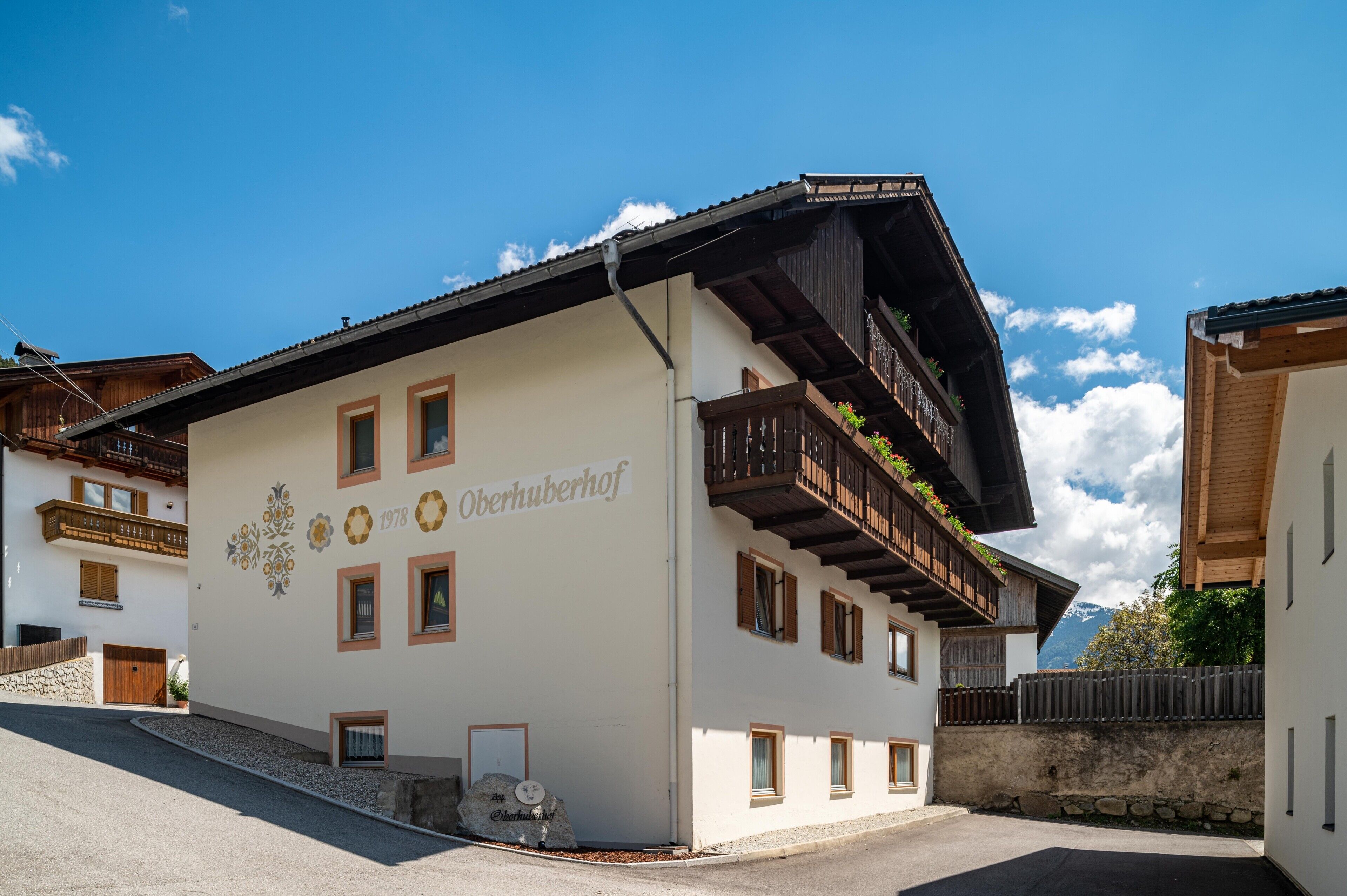 Ein Gebäude mit weißer Fassade, Balkonen mit Holzgeländern und einem Schild mit der Aufschrift 'Oberhuberhof'.