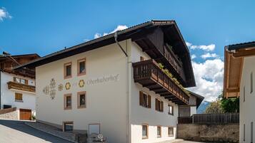 Ein Gebäude mit weißer Fassade, Balkonen mit Holzgeländern und einem Schild mit der Aufschrift 'Oberhuberhof'.