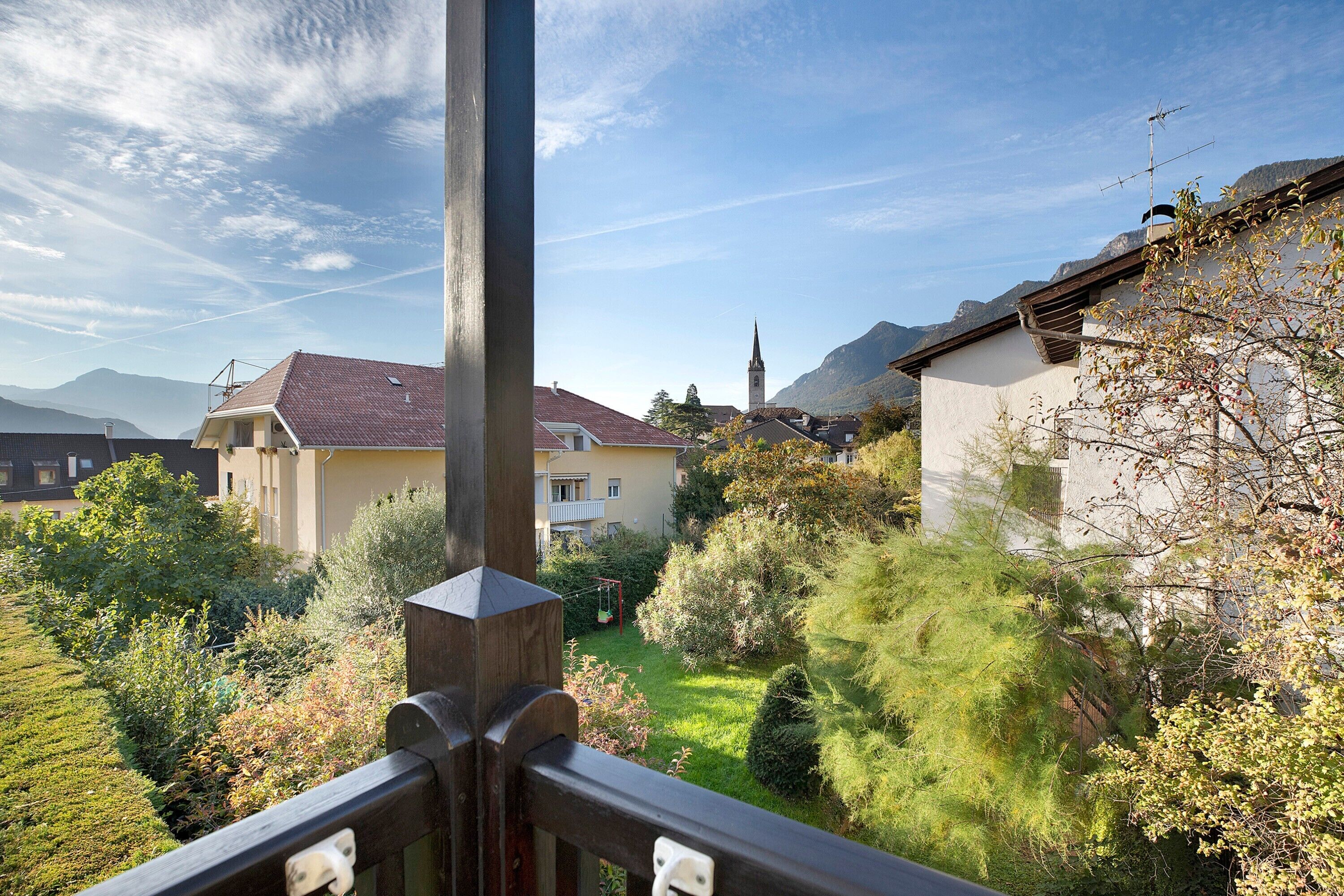 Ein Wohngebiet mit Blick auf einen Kirchturm, einen Garten und ein Gebirge.