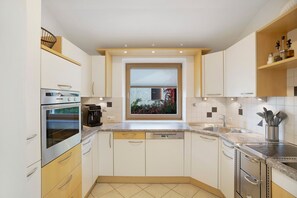 A modern kitchen with built-in appliances, a window with a view, and a countertop with a sink.