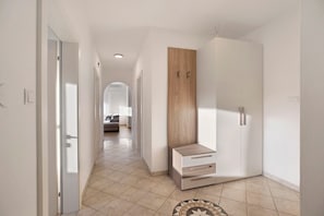 A hallway with a wooden cabinet, a white wardrobe, and a patterned rug.