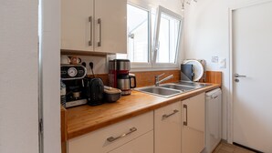 Una cocina compacta con cafetera, hervidor y pileta.