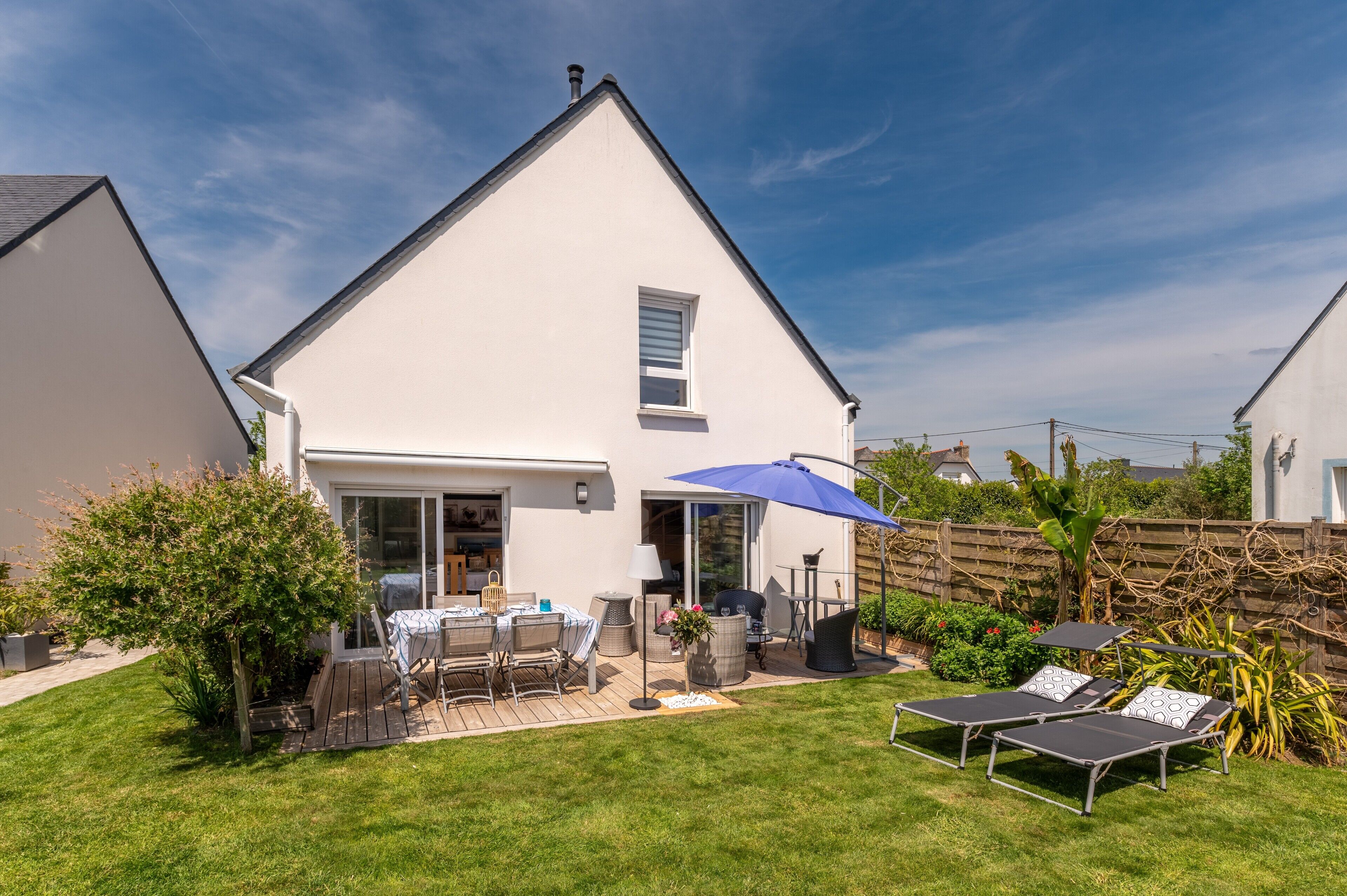 A house with a patio, a table with chairs, a barbecue, and a deck.
