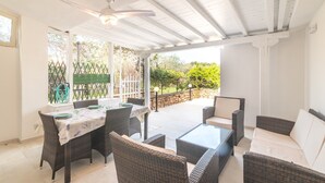 Eine Terrasse im Freien mit Korbmöbeln, einem Tisch und einem Deckenventilator.