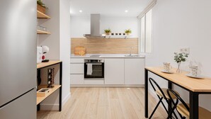 Eine moderne Küche mit weißen Schränken, einem eingebauten Backofen, einer Holz Arbeitsplatte und einem Fenster.