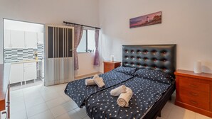 Un dormitorio con cama, mesita de noche, cómoda, ventana con cortinas y vistas al exterior.