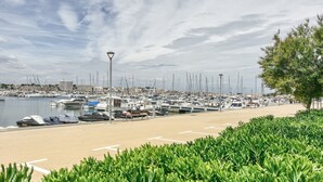 Un puerto deportivo con barcos amarrados, un paseo marítimo de arena y un farol.