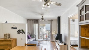Una habitación amplia con una mesa de comedor de madera, un televisor y un balcón con vistas.