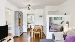 Un espacio habitable compacto con comedor, kitchenette y zona de estar con sofá y cojines.