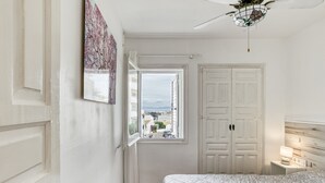 Un dormitorio con cama, mesita de noche, ventana con vistas y puerta.