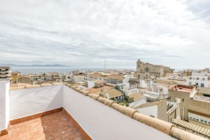 Eine Dachterrasse mit Blick auf eine Küstenstadt, darunter eine markante Kirche und Wohnhäuser.