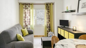 Ein Wohnzimmer mit einer Couch, einem Tisch, einem Fernseher und einem Schrank.