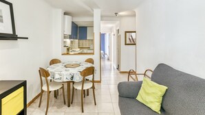 Ein Essbereich mit Tisch und Stühlen, eine Couch mit Kissen und eine Küche im Hintergrund.