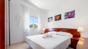 A neatly made bed with white linens, a wooden headboard, and two bedside lamps. - Holiday Home 'Isla Bonita' with Sea Views, Wi-Fi and Air Conditioning (Mont-roig del Camp)