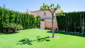 A well-maintained lawn, a tree, and a building with a tiled roof. - Holiday Home 'Isla Bonita' with Sea Views, Wi-Fi and Air Conditioning (Mont-roig del Camp)