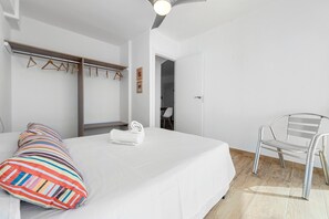 Un dormitorio con cama, una silla, un armario y una puerta que da a otra habitación.