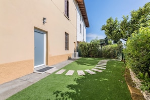 Un edificio residenziale con vialetto lastricato, un piccolo giardino con un sentiero a righe e una porta.