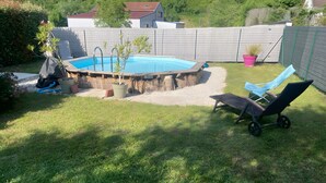 Un giardino sul retro con piscina, una zona giardino e una sedia a sdraio.