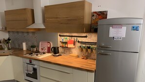 Una cucina con mobili in legno, un frigorifero in acciaio inossidabile, un fornello a gas, un bollitore ed un tostapane.