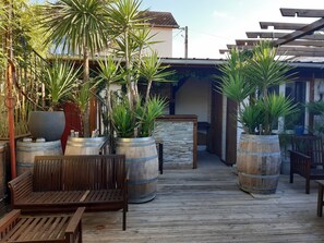 Une terrasse en bois avec un banc, des plantes en pot et une structure en forme de pergola.